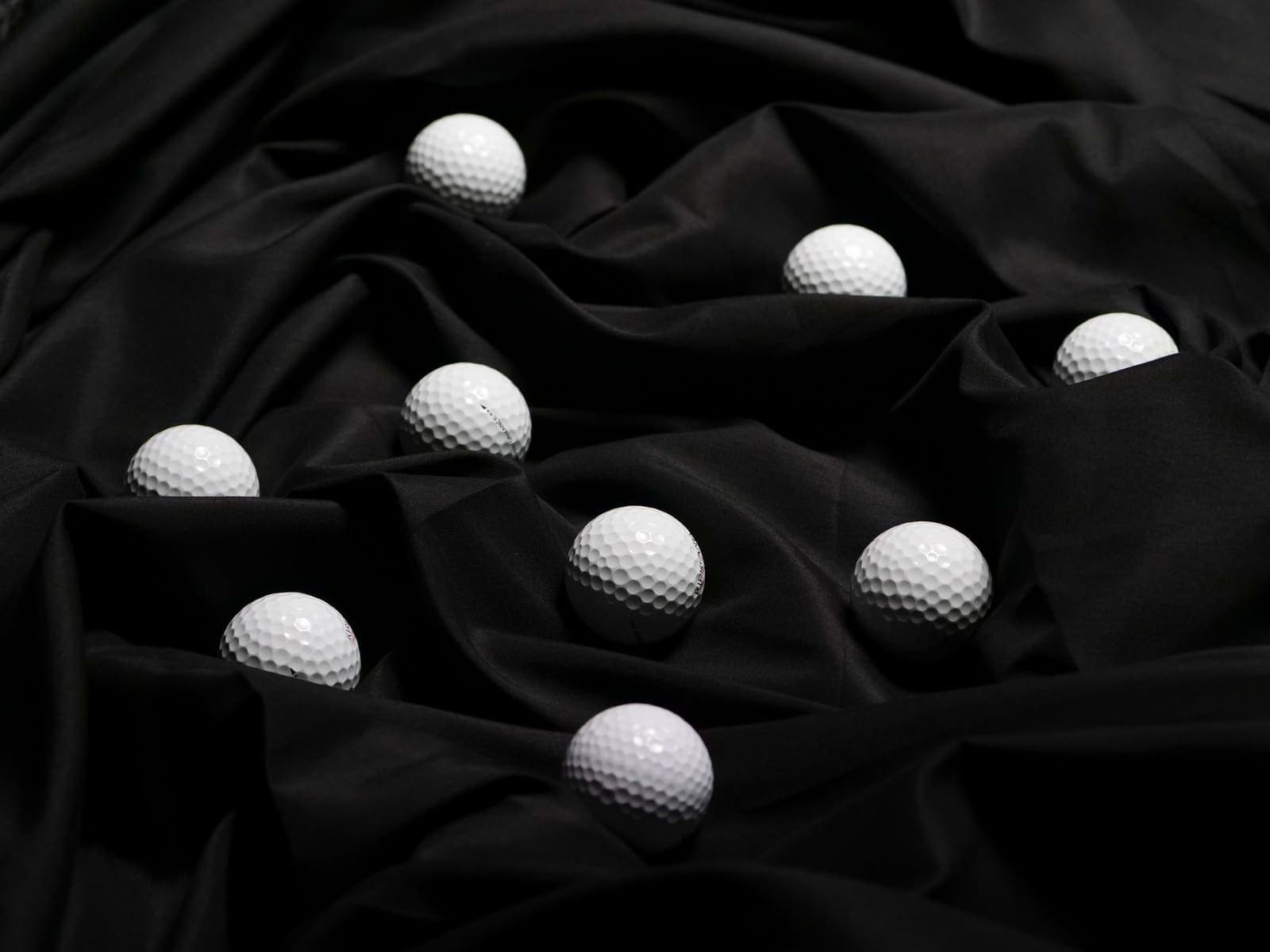 White golf balls scattered on black fabric